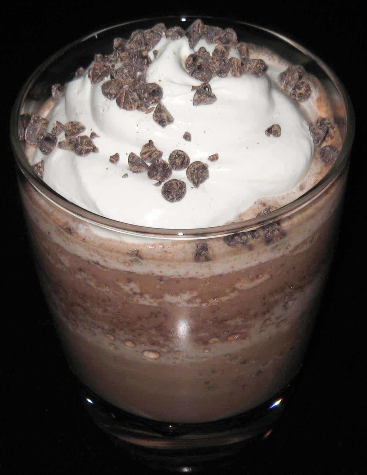 glass of frozen hot chocolate topped with whipped cream and chocolate chips