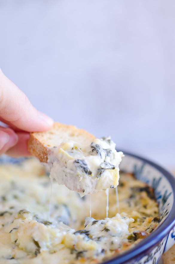 baguette dipped into hot spinach dip