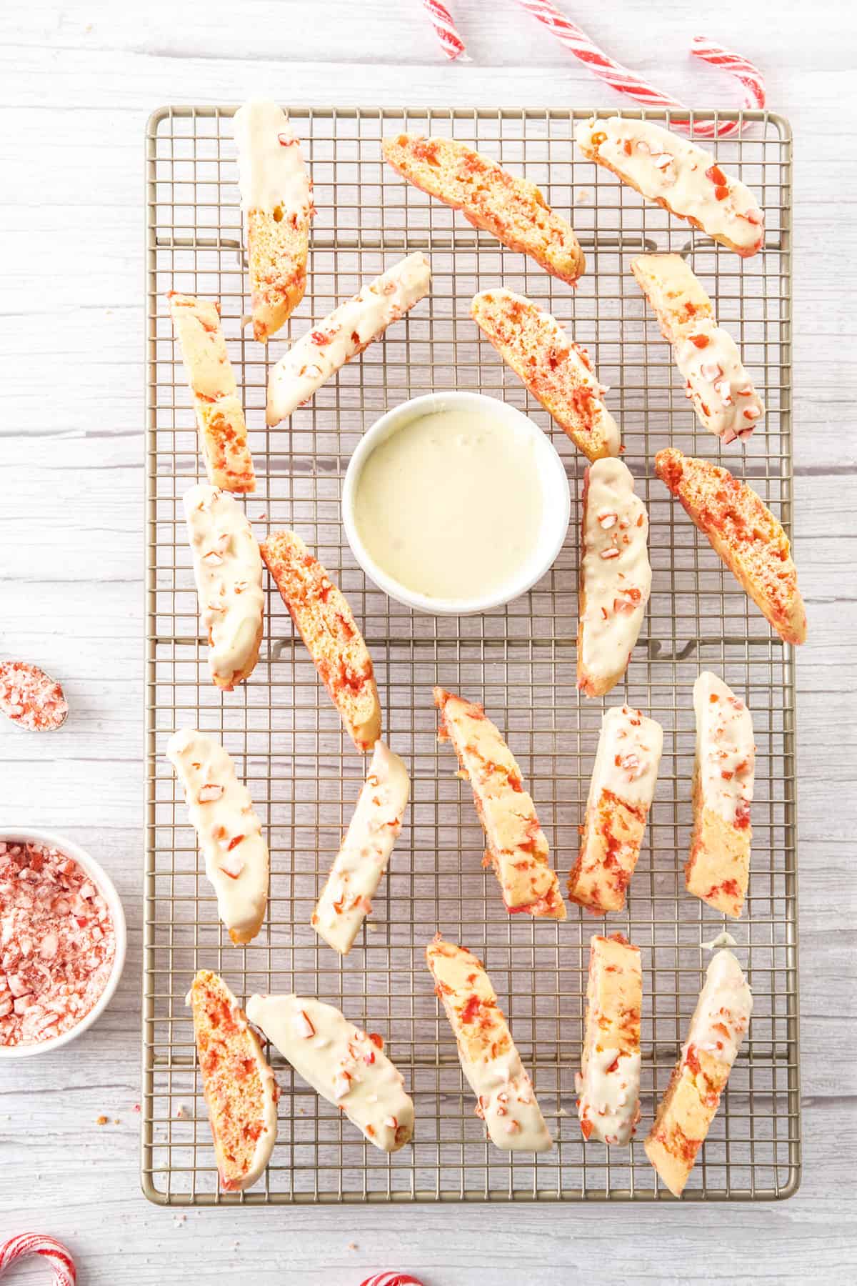 biscotti dipped in white chocolate and sprinkled with candy canes on wire rack