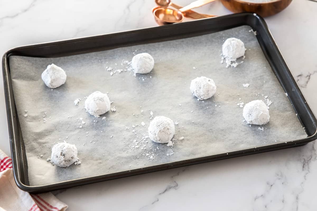 powdered sugar dough balls on cookie sheet before baking