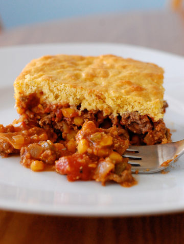 Beef casserole with cornbread topping on a plate with fork