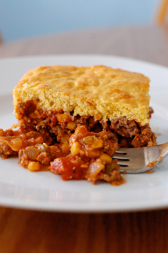 Beef casserole with cornbread topping on a plate with fork