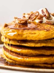 stack of pumpkin spice pancakes with maple syrup and pecans