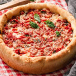 Homemade Chicago-style deep dish pizza baked in a cake pan with melted cheese and tomato sauce