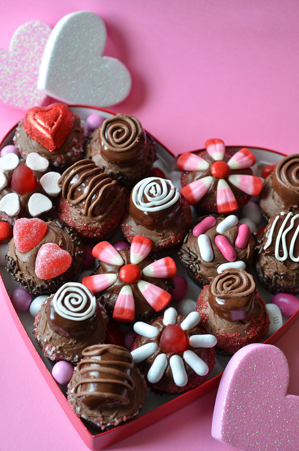 heart shaped box full of decorated cupcakes and candies