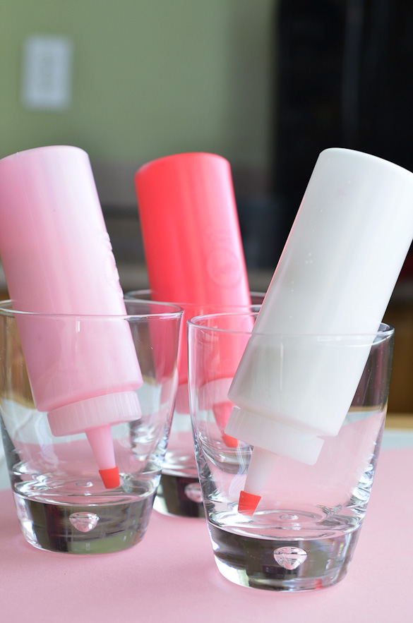 squeeze bottles filled with icing upside down in glasses