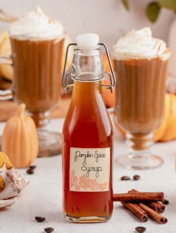 pumpkin spice syrup in a bottle with coffee drinks in background