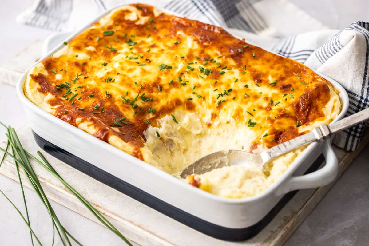 cheese mashed potatoes in a casserole dish with spoon