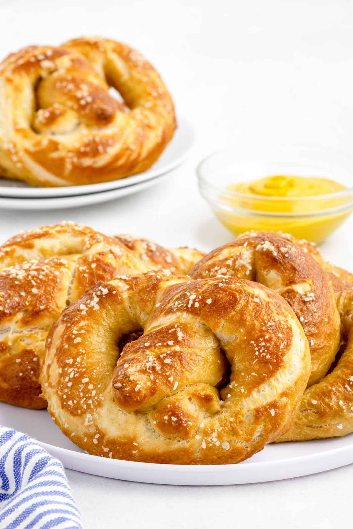 plate of soft pretzels with yellow mustard in background