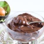 bowl of creamy chocolate pudding with avocado in background