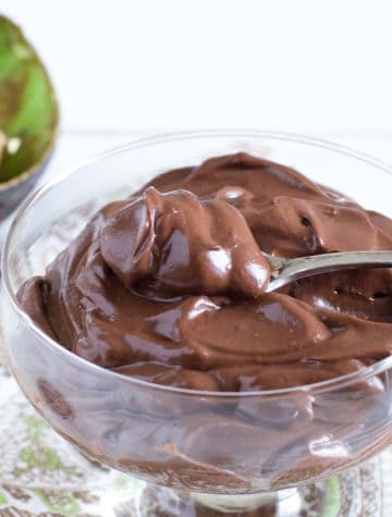 bowl of creamy chocolate pudding with avocado in background