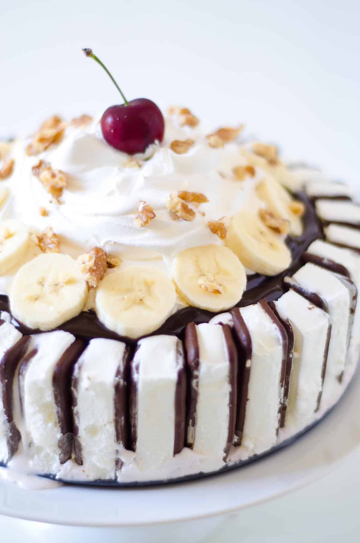 ice cream cake with ice cream sandwiches and bananas and cherry on top