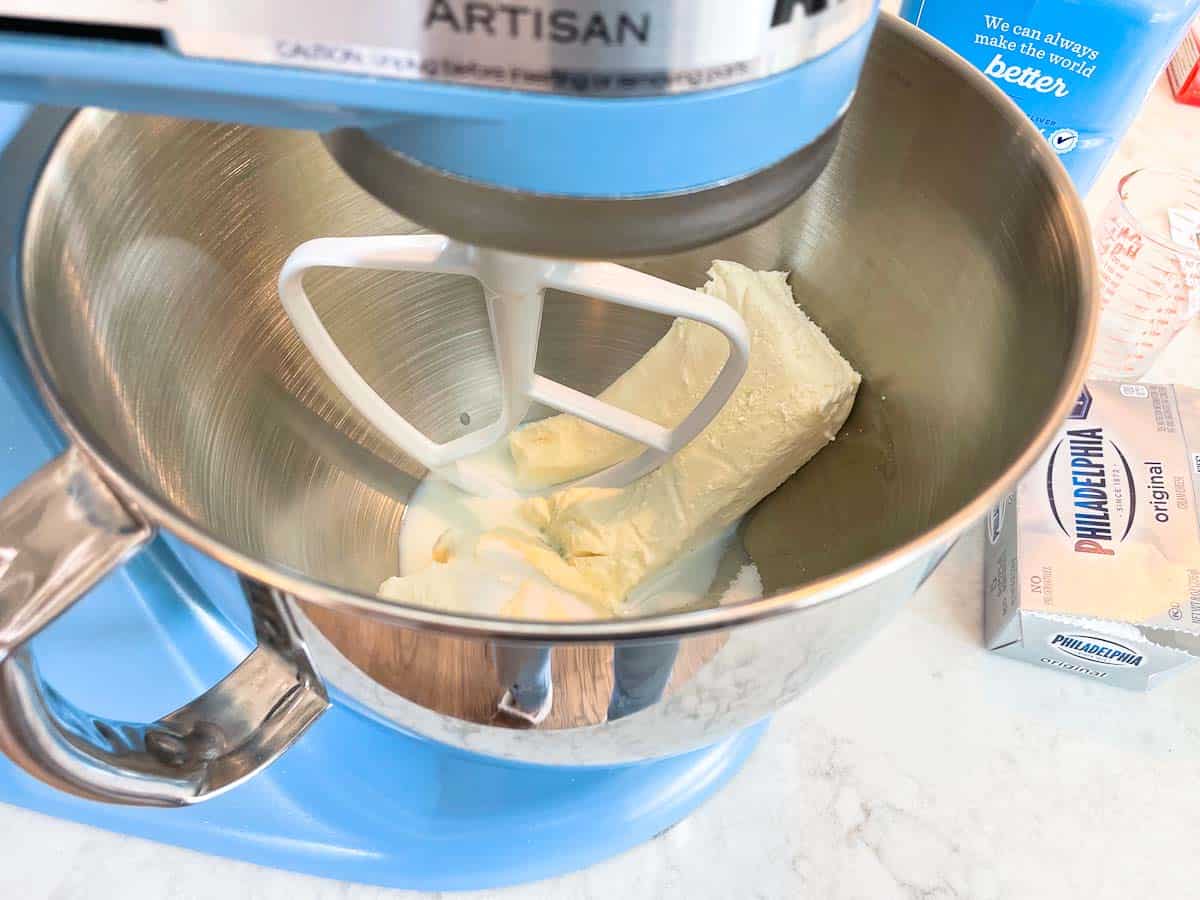 mixing cream cheese with sugar and milk in stand mixer