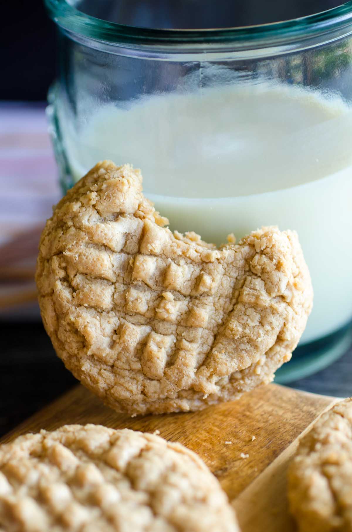 bite out of peanut butter cookies with glass of milk