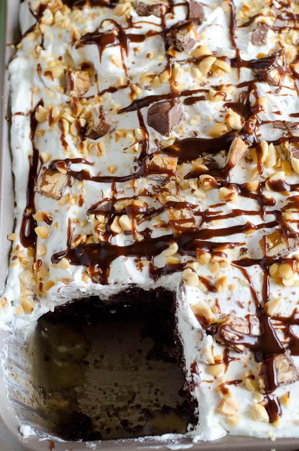 Snickers Cake is a dessert to please a crowd.  Boxed cake mix is the base for this Snickers Cake that is then soaked in caramel sauce and garnished with a whipped Snickers topping.