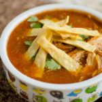 bowl of mexican soup topped with tortillas