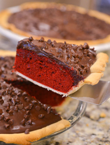 A slice of red velvet cake in a pie pan with chocolate chip topping