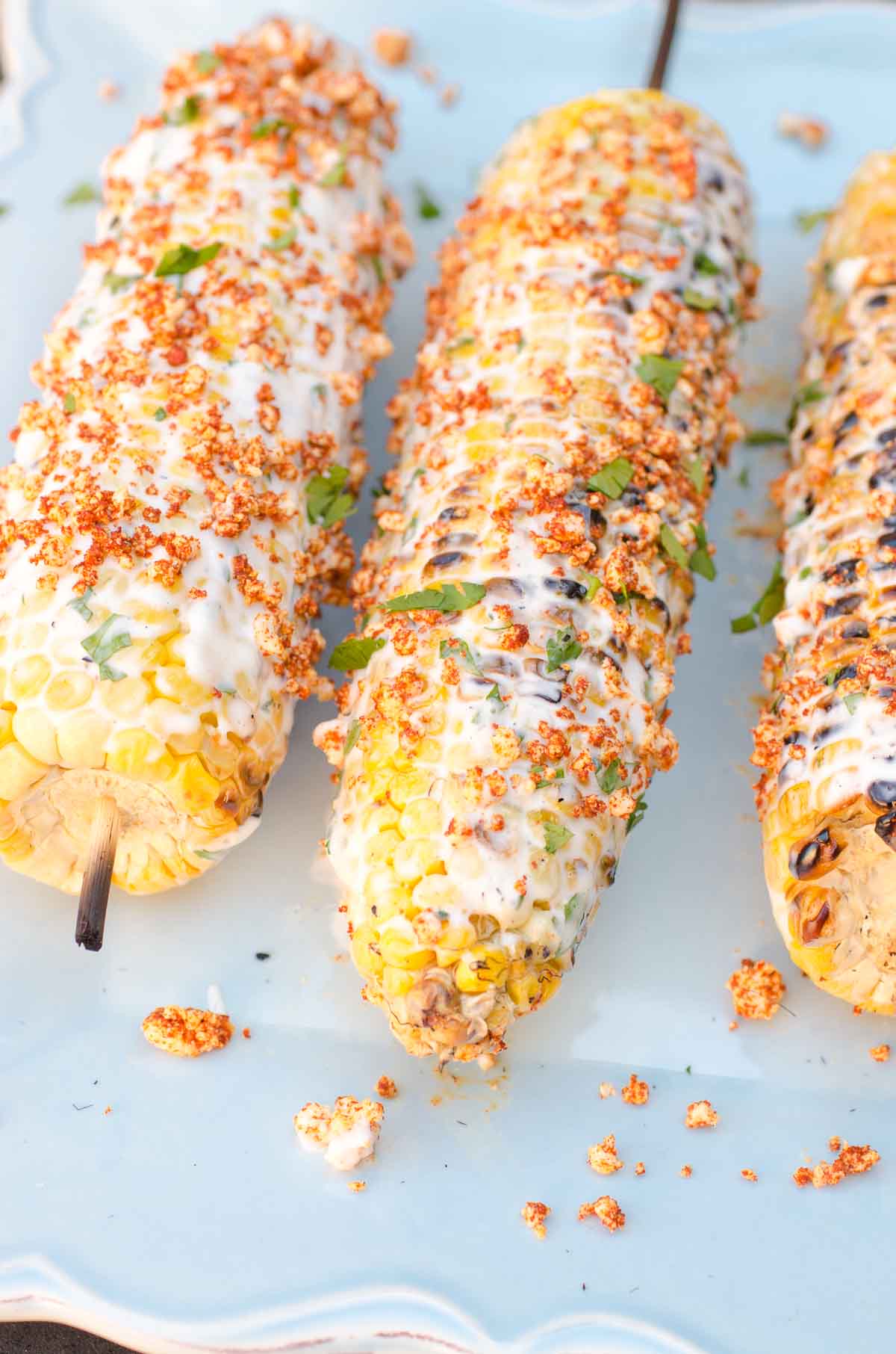 corn on cob on skewers with creamy dressing on blue plate