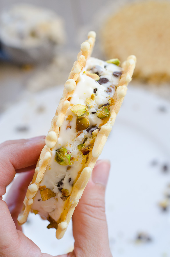 Fingers holding Cannoli Ice Cream Sandwich.