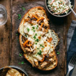 open faced chicken sandwich on sourdough with a side of potato chips and coleslaw