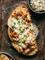 open faced chicken sandwich on sourdough with a side of potato chips and coleslaw