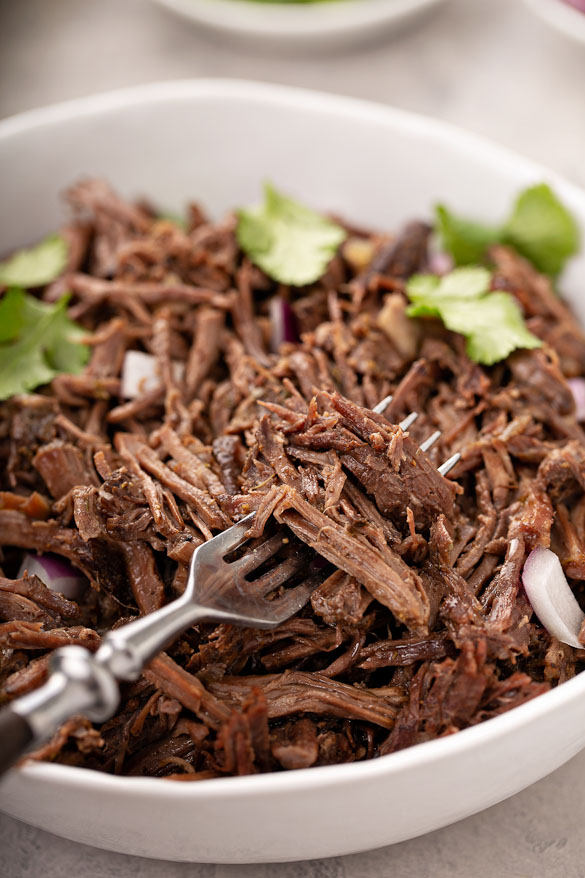 shredded beef in a bowl with a fork