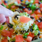 Seven Layer Dip Recipe - The easiest and quickest Mexican dip recipe with layers of refried beans, guacamole, taco seasoned sour cream and more!