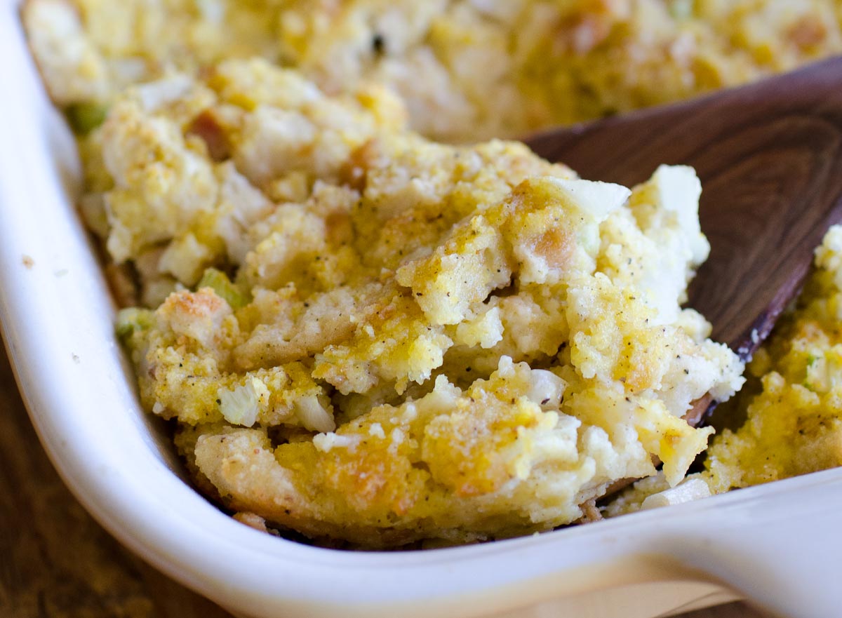 scooping cornbread dressing in pan