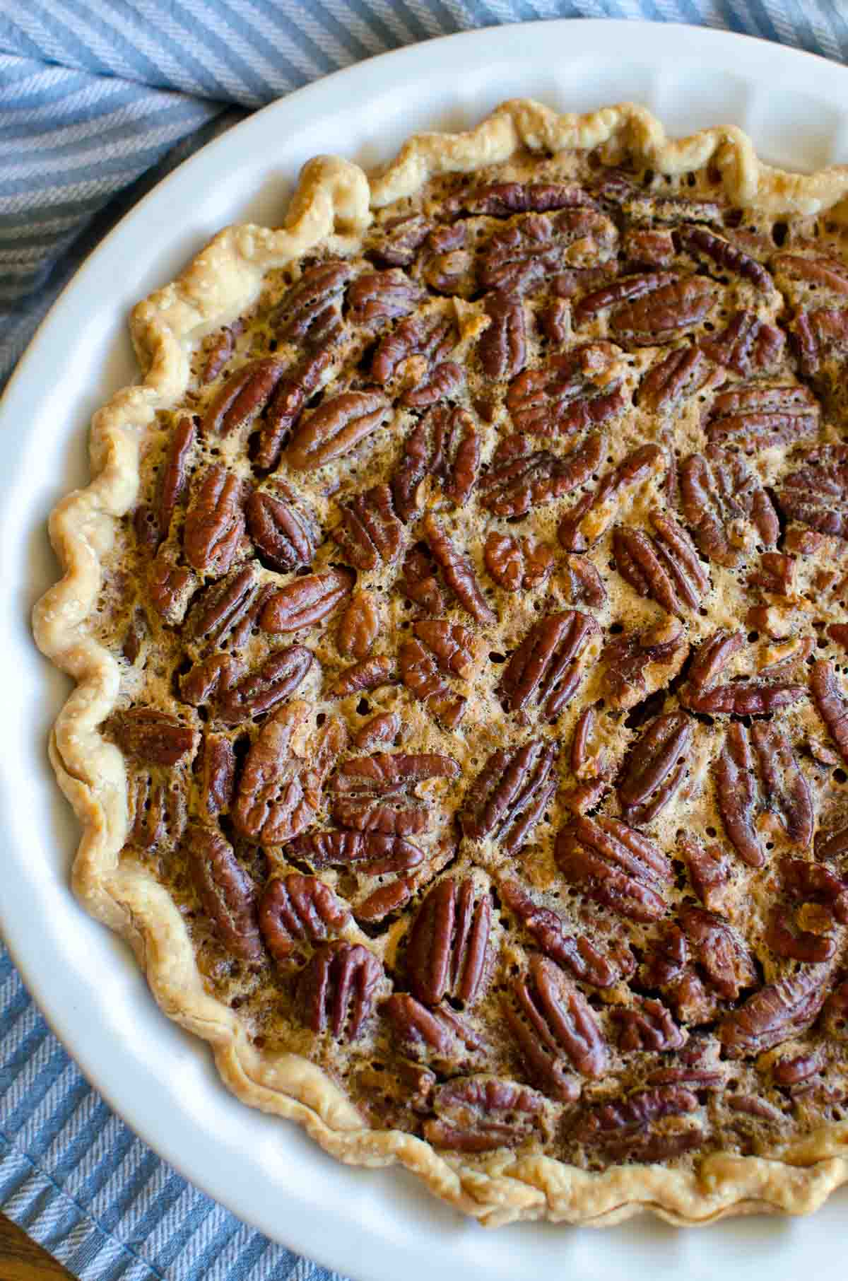 pecan pie in a white pie plate with blue line towel