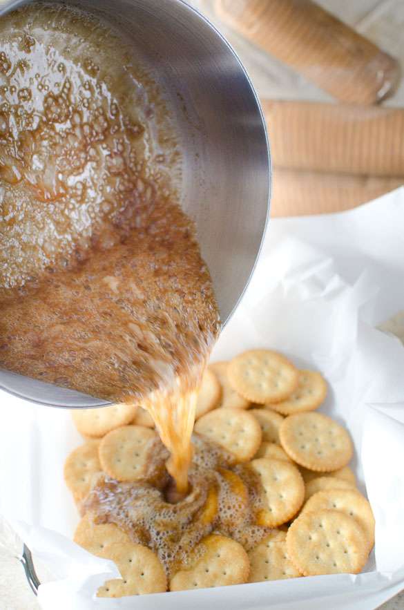 pouring hot caramel onto pan of ritz crackers