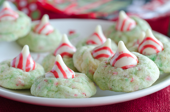 Sugar Cookie Candy Cane Blossoms are peppermint sugar cookies topped with Hershey's Candy Cane Kisses. They are a spin-off of the traditional peanut butter kiss blossoms. You will love these Candy Cane Blossom cookies because they are easy to make, delicious to eat, and perfect for your Christmas cookie swap!