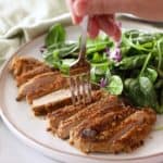 sliced almond crusted pork on a plate with salad greens
