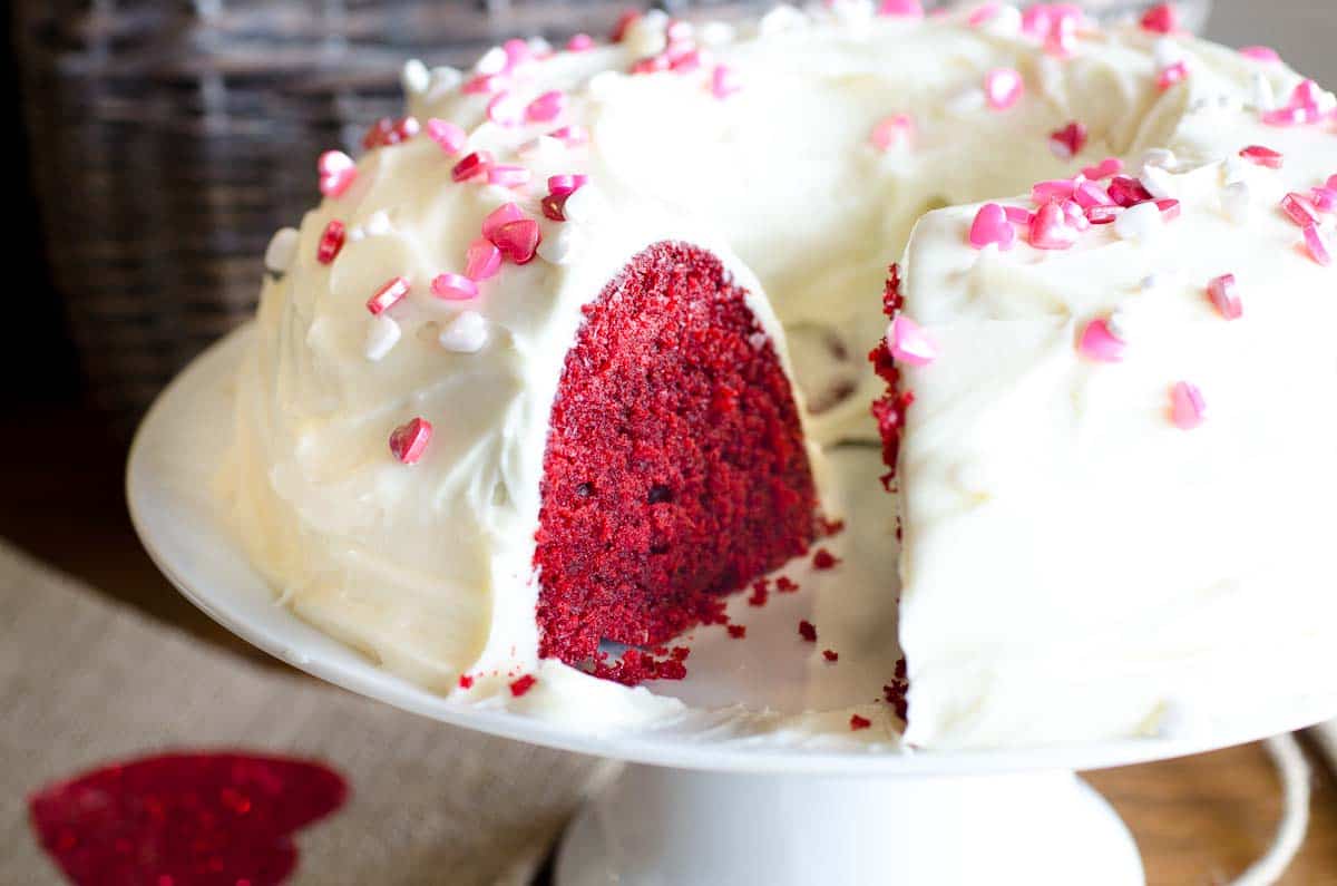 red velvet bundt cake with white frosting and heart sprinkles