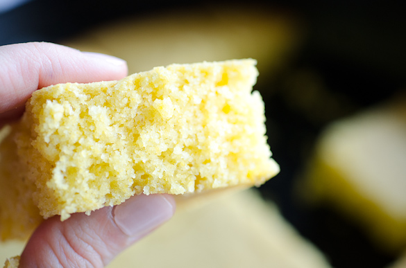 Fingers holding a piece of fluffy cornbread.