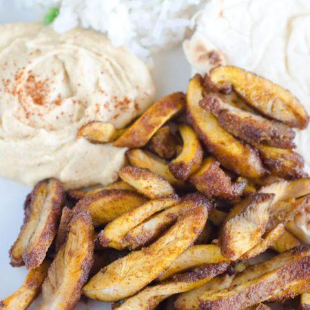 Chicken shawarma on a plate with hummus, rice and pita.