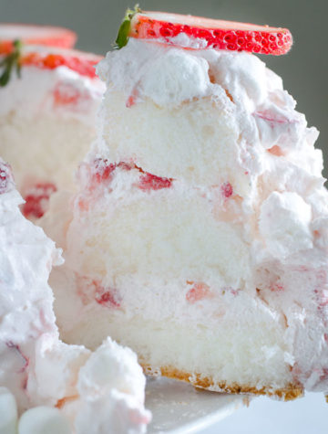 Slice of layered angel food cake with strawberry marshmallow frosting.