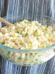 holding a glass bowl full of macaroni salad