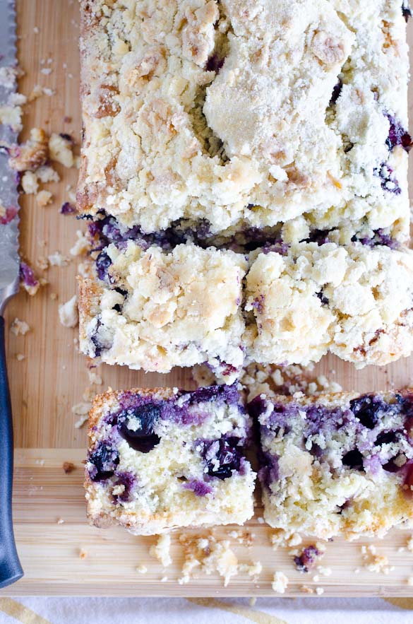 Slices of blueberry muffin bread on cutting board with knife.