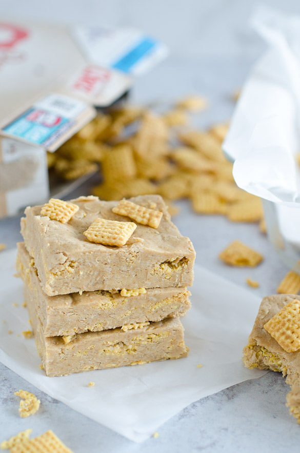 Stack of homemade protein bars topped with Chex cereal and cereal spilled in the background