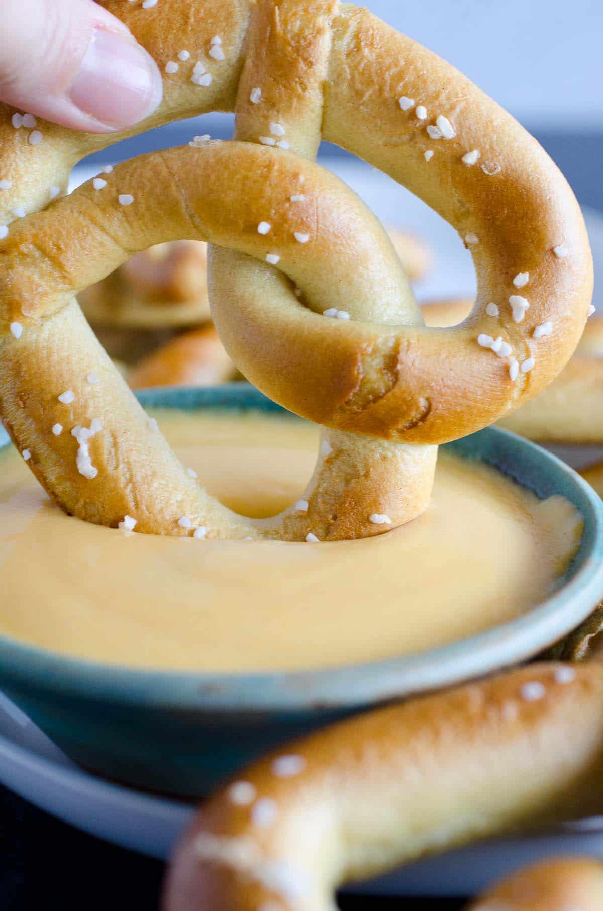 salted soft pretzel dipped into bowl of beer cheese