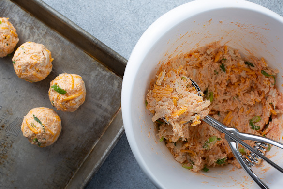 scooping chicken mixture from bowl onto baking sheet