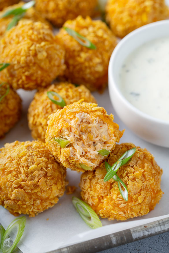 bite out of buffalo chicken cheese ball stacked on a plate with ranch dip