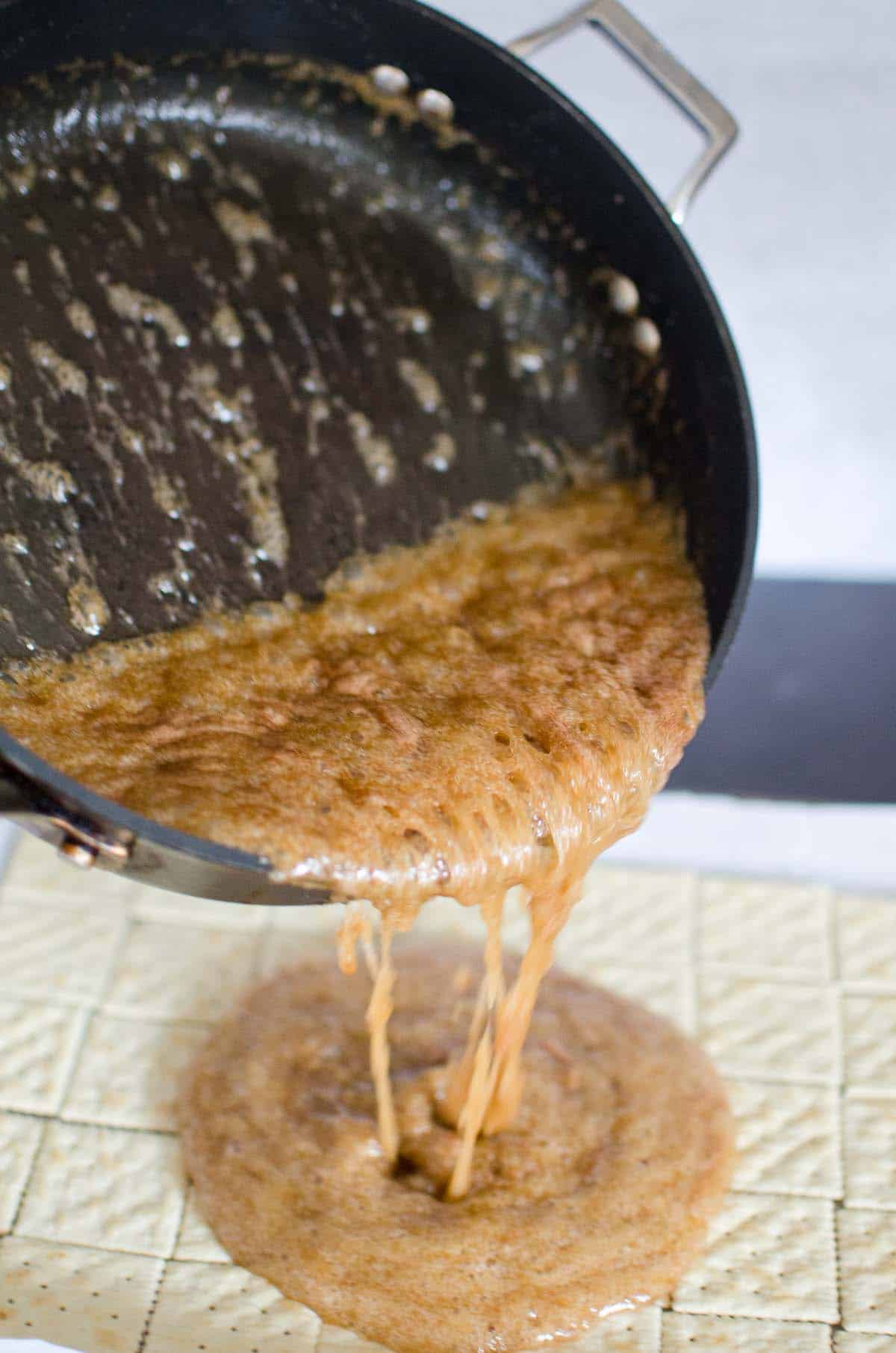 pouring hot caramel onto pan of saltine crackers
