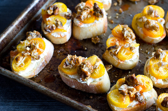 crostini appetizer topped with kumquats, walnuts and spicy honey