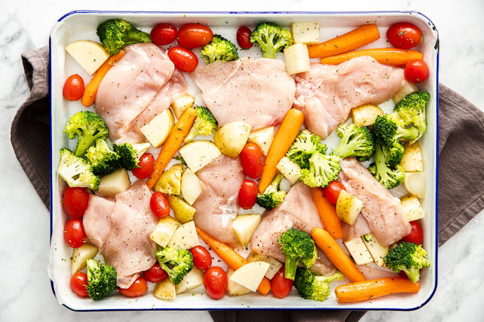 raw chicken and veggies on baking sheet