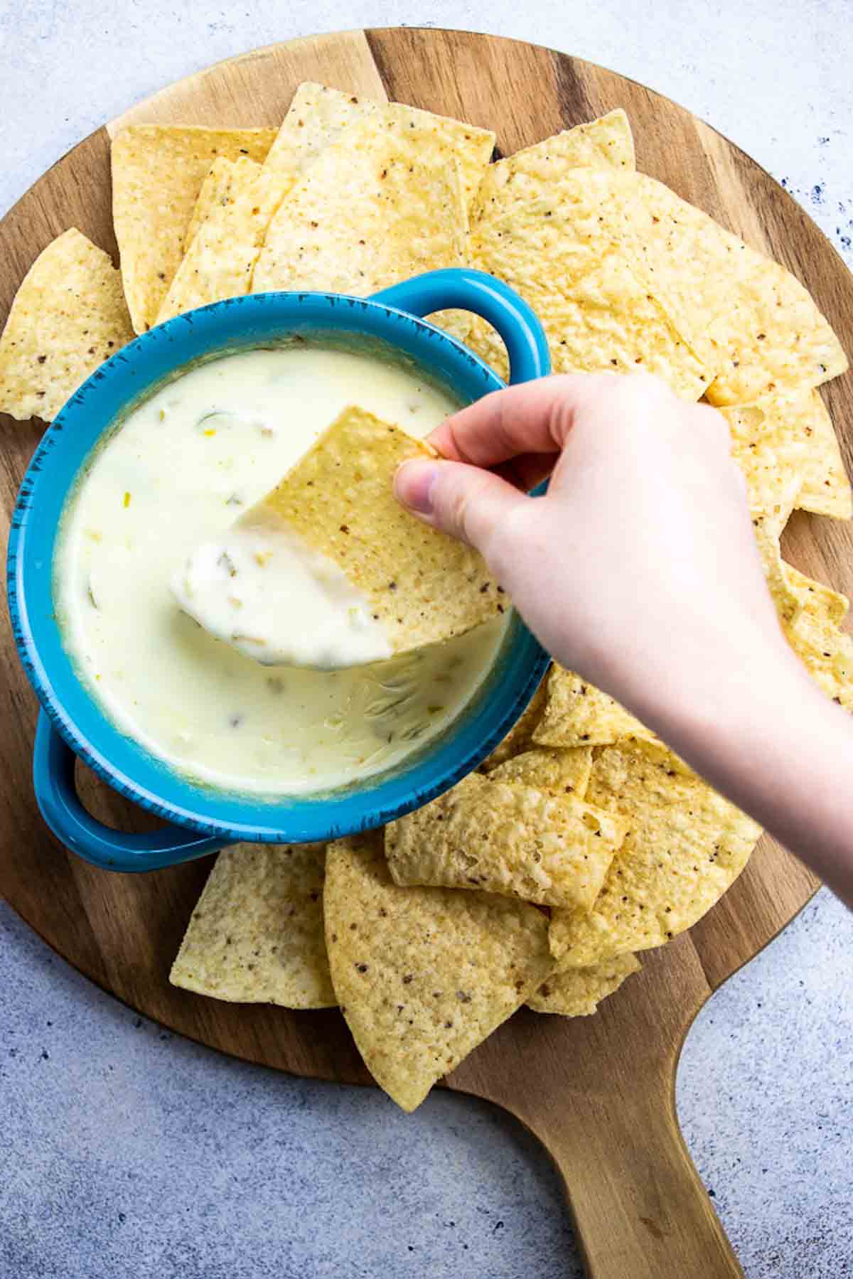 bowl of white cheese dip on a cutting board with tortilla chips