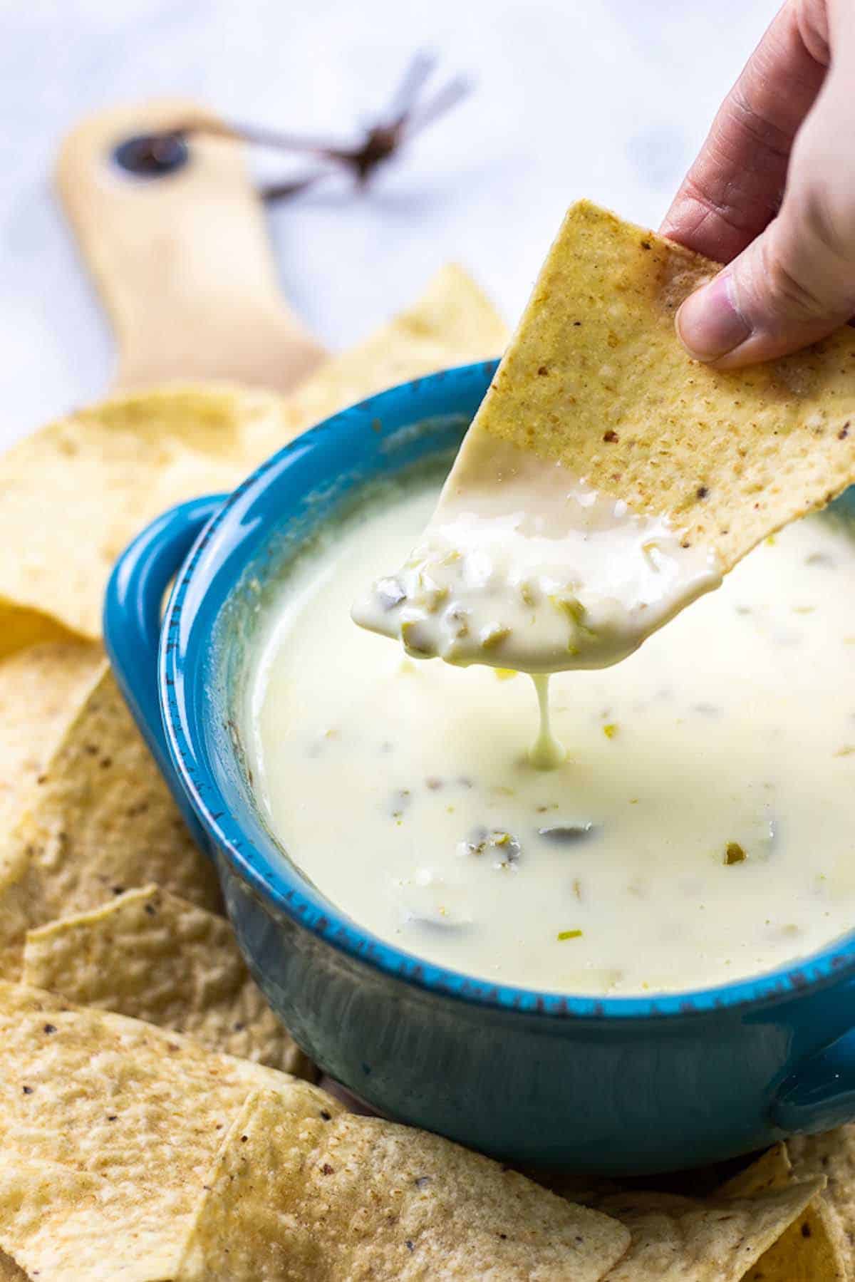 tortilla chip dipped into bowl of white cheese dip