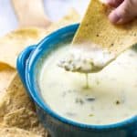 bowl of cheese dip with tortilla dipped in