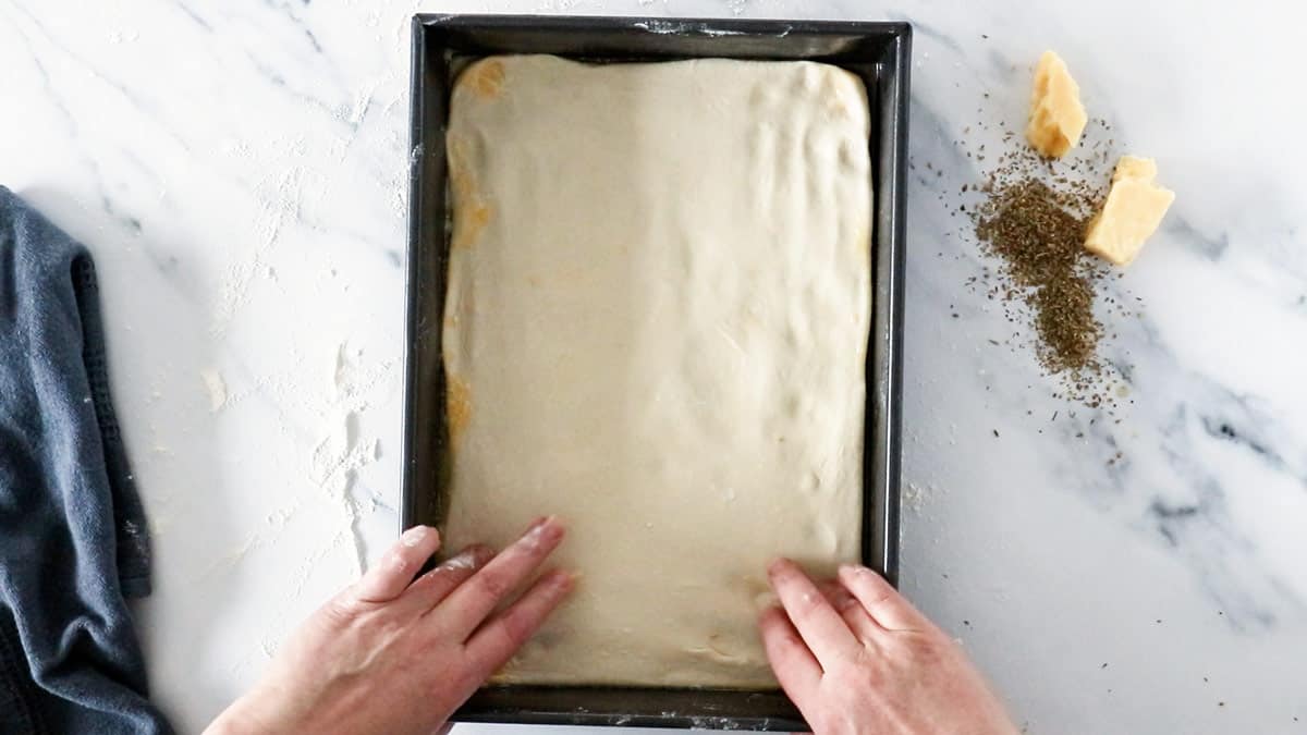 pressing breadsticks dough into baking dish