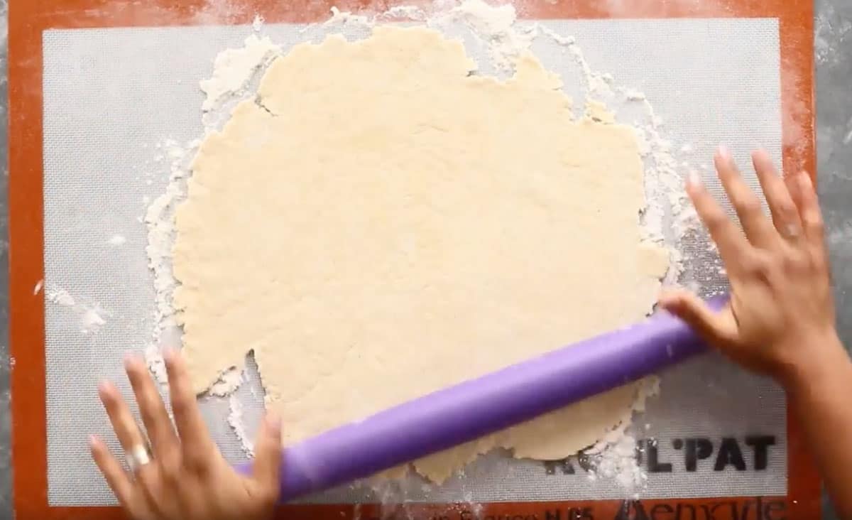 rolling dough with purple rolling pin on silpat mat